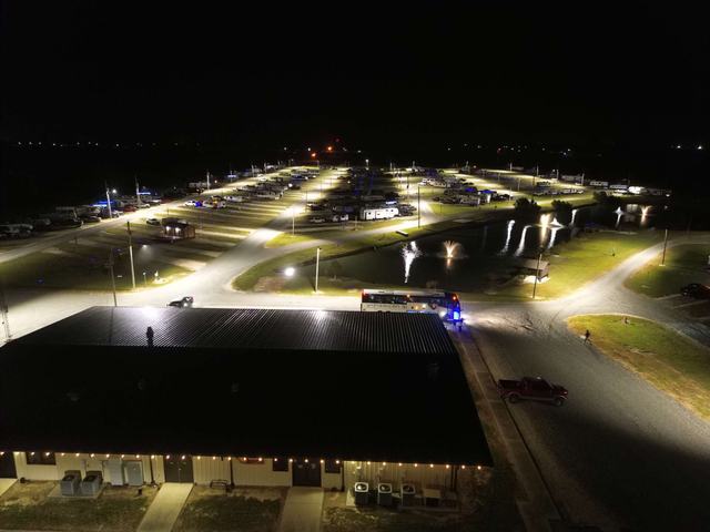 Night aerial view of American Dream RV Park with lit sites, pond fountains, and main building