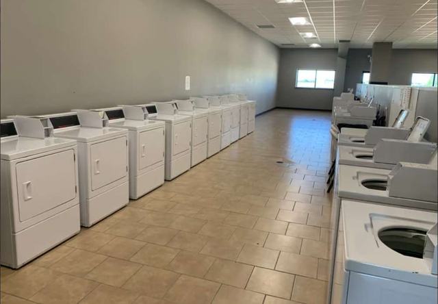 Laundry room with rows of white washers and dryers on a tiled floor