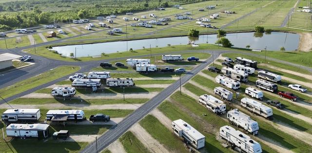 Aerial view of RVs parked in rows along paved roads beside a pond