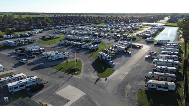 Aerial view of The Gates at McNeese RV Park with rows of RVs beside a pond