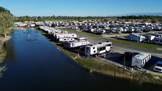 Aerial view of The Gates at McNeese RV Park with RVs lining a pond with fountains