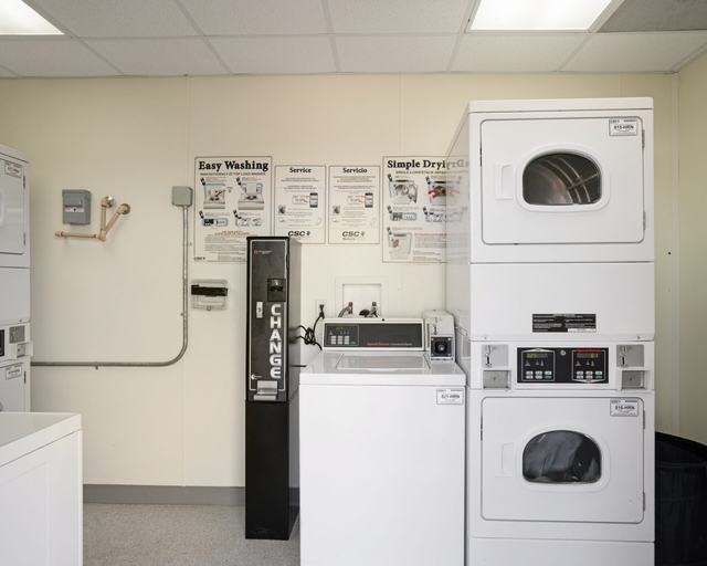Laundry room with stacked dryers, a washer, and a change machine