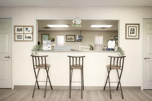 Office reception counter with three bar stools and framed pictures on the wall