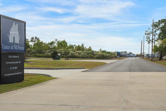 Entrance sign for Gates at McNeese beside the paved driveway into the park
