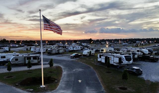 American flag over The Gates at McNeese RV Park at sunset with lit RV sites