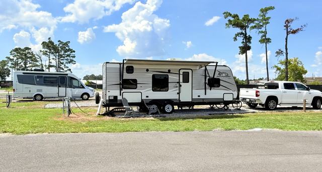 Travel trailer, camper van, and white pickup parked on grassy sites