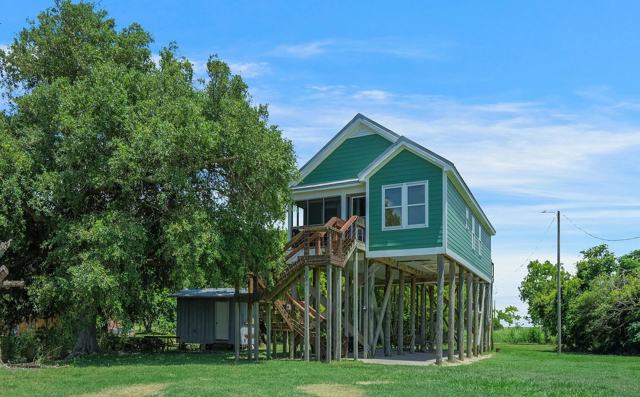 Pecan Island Camp raised green house with wooden staircase and small shed nearby