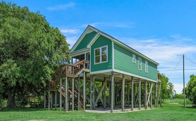 Side view of Pecan Island Camp green stilt house with covered parking area below