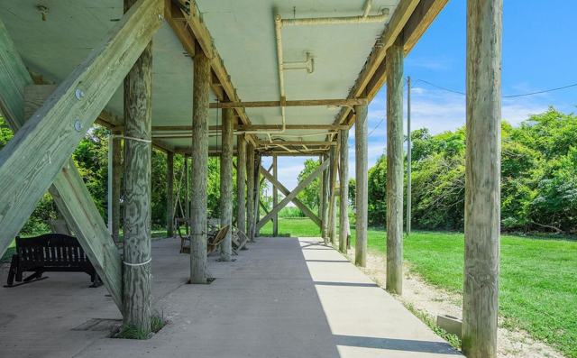 Covered concrete area beneath the house with wooden support posts and cross bracing