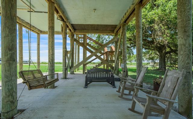 Shaded area under the house with porch swing, bench, and wooden rocking chairs