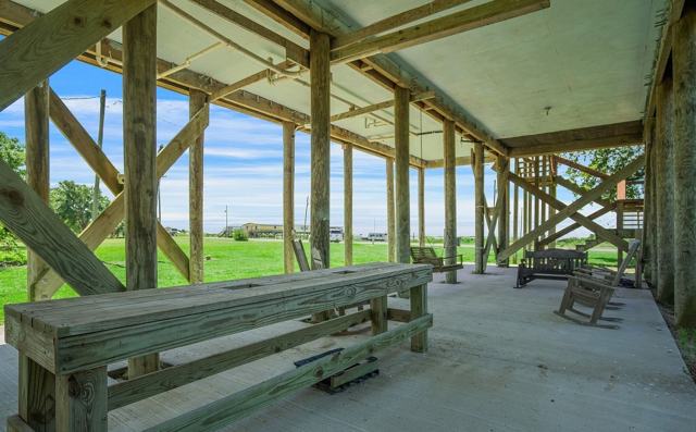 Long wooden workbench under the elevated house overlooking a grassy field