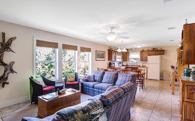 Open living area with plaid sofas, ceiling fan, and kitchen in the background