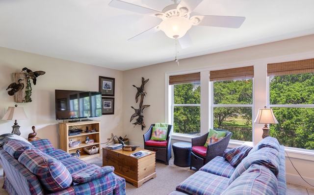 Living room with plaid sofas, wicker chairs, television, and large windows