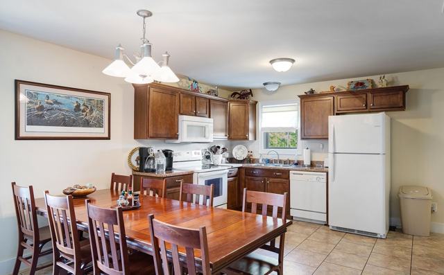 Kitchen with wooden cabinets, white appliances, and large wooden dining table with chairs