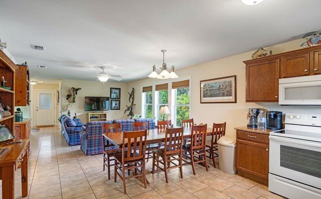 Open dining area with long table leading into living room with tile floors