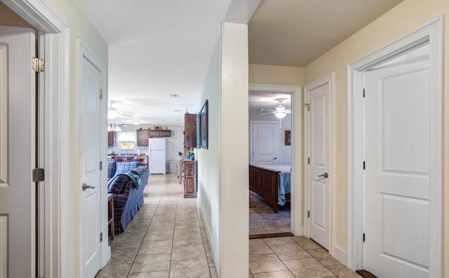 Tiled hallway with white doors leading to living area and bedroom