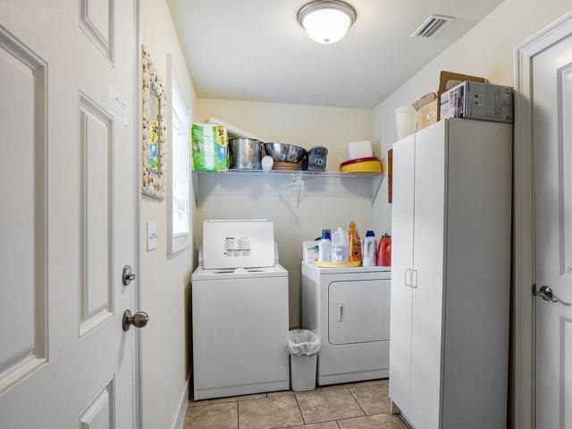 Laundry room with washer, dryer, wire shelf, and white storage cabinet