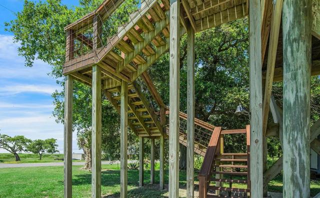 Wooden exterior staircase with wire railings leading up the elevated house