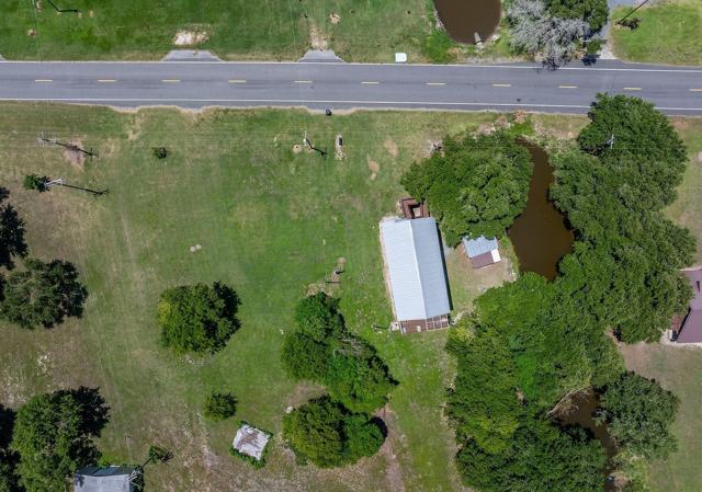 Overhead aerial view of Pecan Island Camp roof, shed, trees, and pond by road