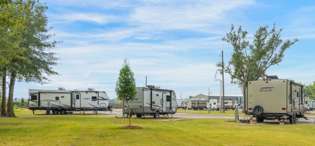 Travel trailers parked on grassy sites under a blue sky at Rustic Oak RV Park