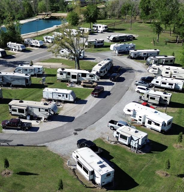 Aerial view of Rustic Oak RV Park with RVs along a curving road near a pond