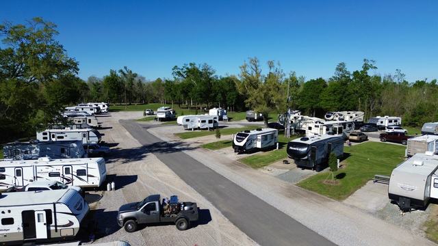 Elevated view of RVs lining a paved road with gravel sites and trees