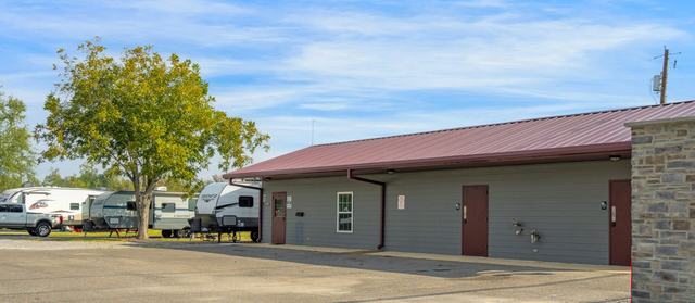 Gray building with a red metal roof beside parked RVs and a tree