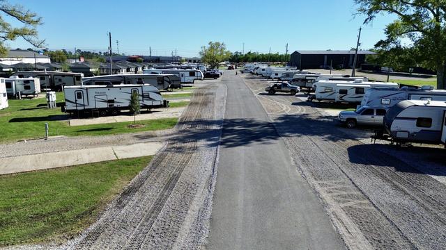 Paved lane lined with gravel RV sites and parked travel trailers